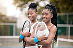 African american professional tennis players holding rackets on the court. Young women ready to compete in a tennis match. Portrait of fit young women holding their tennis rackets on the court