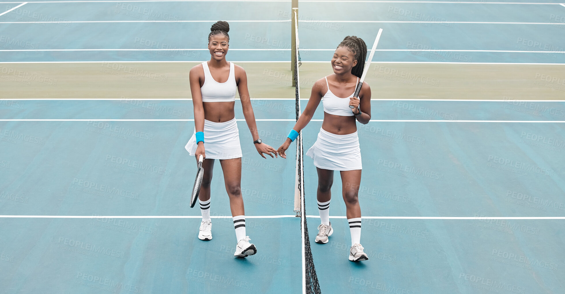 Buy stock photo Tennis players holding hands after a match. Two women walking by the net on the tennis court holding hands. Young friends bonding after tennis practice. Happy tennis players on the court