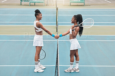 Two women handshake after tennis match. Young friends greet each other before tennis practice. African american athletes bonding after a tennis match. Girls shaking hands over a net on the court