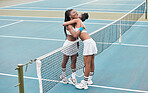 Carefree tennis players hugging over the net. African american women embracing on the tennis court. Happy friends enjoying a hug after a game of tennis. Friends bonding on the tennis court