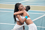 Happy women hugging after a tennis match. Two friends bonding on the tennis court after a match. Carefree professional tennis players embracing over the net on the court.Girls playing tennis