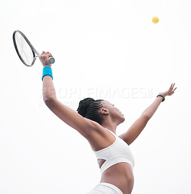 Young tennis player throwing a ball into the air. Fit athlete waiting to hit a ball during a tennis match. African american athlete ready to hit a ball during tennis practice.