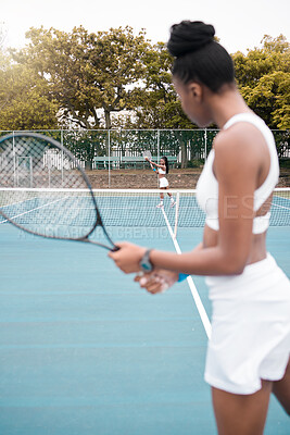 Young woman serving during a tennis match. Two women playing a game of tennis together. African american athletes enjoying a practice match of tennis. Women standing on the court