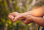 Above shot of a caucasian man suffering with cramp in his forearm while out hiking in the woods. Superimposed CGI highlighting an injury to a young male's arm while exercising outdoors in the forest
