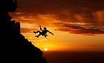 Unrecognizable adrenaline junkie doing extreme sports. Unknown man doing mountain climbing at sunset. Dark shot of a young male passionate about his fitness while doing his favourite hobby