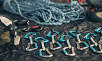 Closeup shot of a variety of carabiner hooks, rope, and other safety equipment used for rock or mountain climbing against a dark background. Needed for people passionate about extreme sport