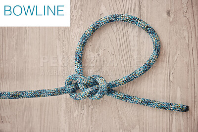 Above shot of hiking rope tied in a knot against a wooden background in studio. Bowline knot. A knot for every situation. Strong rope to secure safety while mountain climbing or doing extreme sports