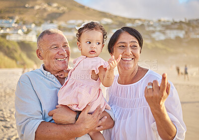 Mature mixed race couple and their granddaughter at the beach. Cute little girl spending time with her grandfather and grandmother outside. Happy grandparents bonding with their grandchild outdoors