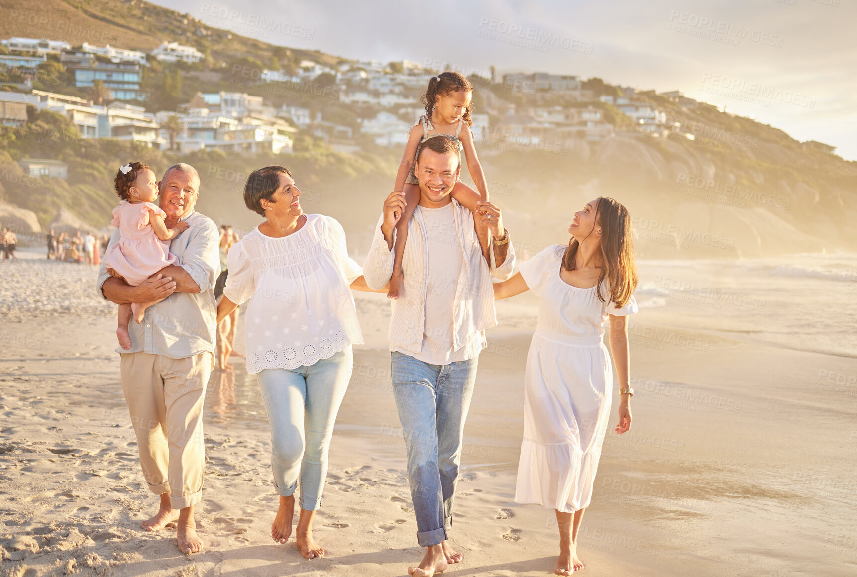 Buy stock photo Happy mixed race family of six walking on the beach. Two cute sisters enjoying the sand and sea with their mom, dad, grandmother and grandfather. Grandparents with their kids and grandchildren