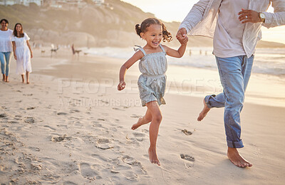 Buy stock photo Cute little girl running hand in hand with her mixed race dad on the beach. A daughter and her father holding hands while playing in the sand next to the sea at sunset. Family bonding at the coast