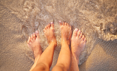 Buy stock photo Above shot of the feet of a caucasian couple in the ocean while standing on the sand at the beach. Romantic people sharing an intimate moment during a date by the seaside. Love and togetherness