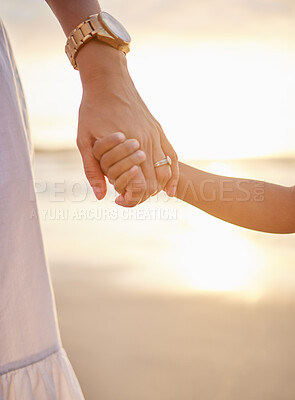 Buy stock photo Closeup of unknown mixed race mother holding her little son or daughter's hand while bonding together on the beach at sunset. Hispanic child showing trust in single mother. Loving and caring parent