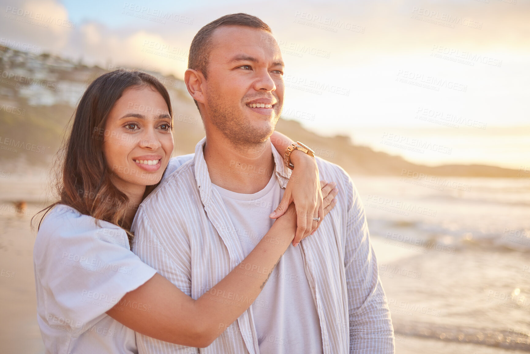 Buy stock photo Affectionate young mixed race couple sharing an intimate moment on the beach. Happy husband and smiling wife enjoying a summer day by the sea. They love spending time together on the coast at sunset