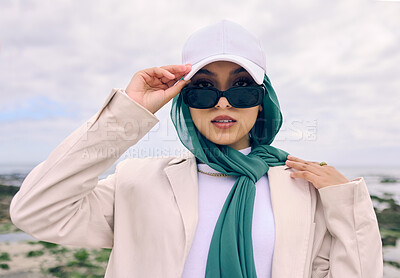 Buy stock photo Portrait, fashion or sunglasses with a saudi woman outdoor in a cap and scarf for contemporary style. Islam, face and hijab with a trendy young muslim or arab person posing outside in modern clothes