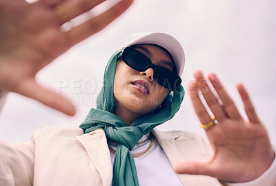 Buy stock photo Low angle portrait, woman and city for muslim fashion with gen z aesthetic, streetwear and sky background. Young islamic girl, student and clothes with sunglasses, freedom and outdoor travel in Dubai