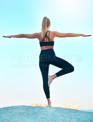 Rearview beautiful woman practising yoga exercise on the beach. Young female athlete stretching while working out outside. Finding inner peace and balance. Focused on health and a fitness lifestyle