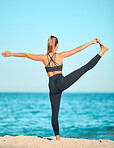 Rearview beautiful woman practising yoga exercise on the beach. Young female athlete stretching while working out outside. Finding inner peace and balance. Focused on health and a fitness lifestyle