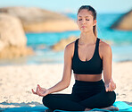 Beautiful woman meditating while practising yoga exercise on the beach. Young zen female athlete working out outside. Finding inner peace, balance and getting healthy. Focused on a fitness lifestyle