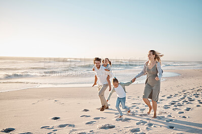 Buy stock photo Happy parents walking with their children on the beach. Young family on vacation by the ocean. Children enjoying freedom on the beach with their parents. Loving family on a getaway together