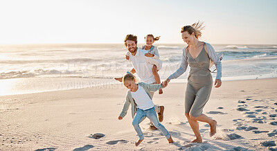 Buy stock photo Carefree family playing on the beach together. Happy family on vacation by the ocean together. Little girls playing with their parents on holiday. Caucasian family bonding on the beach
