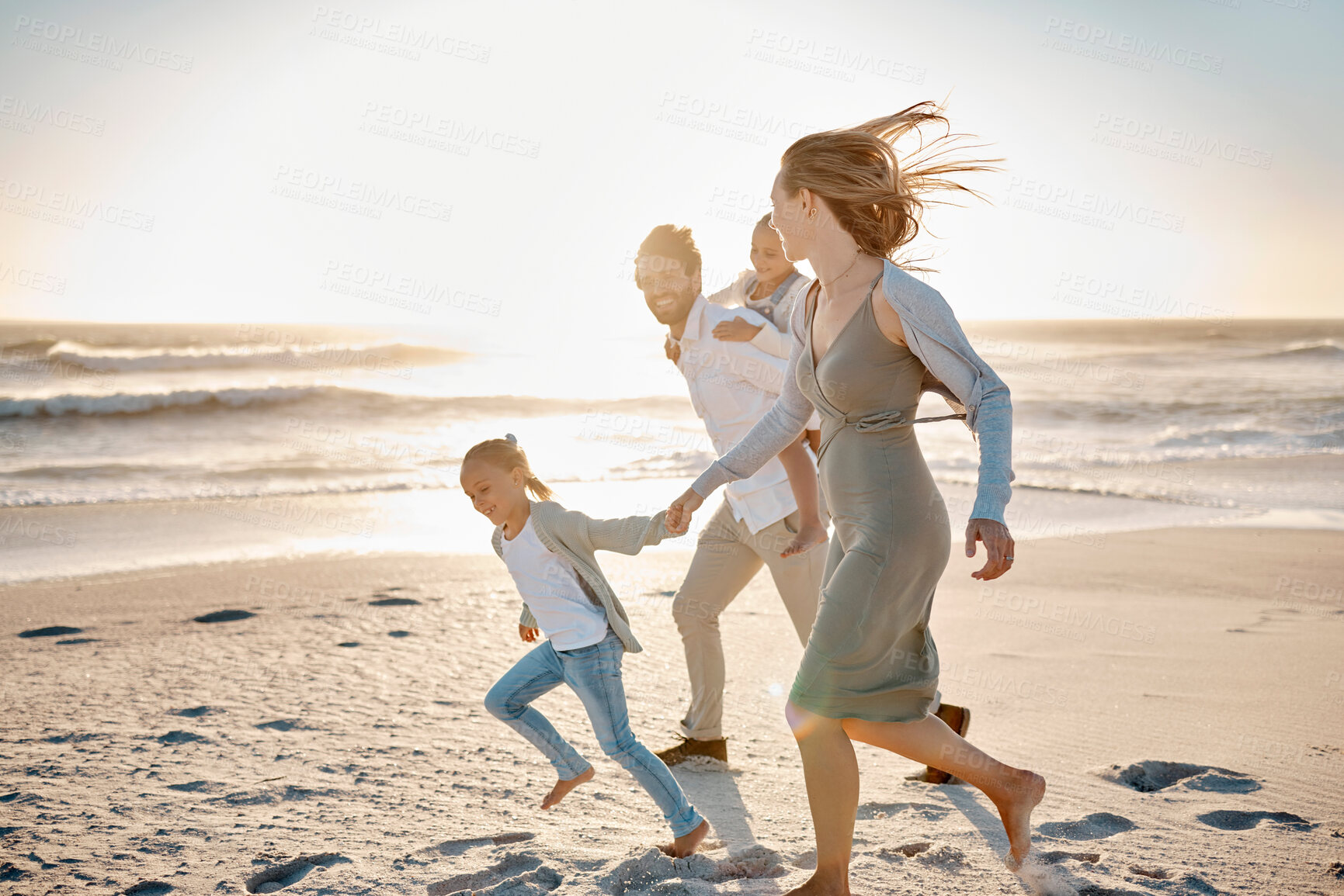 Buy stock photo Carefree family having fun on the beach. Happy family playing on the beach on holiday. Caucasian family enjoying a beach vacation. Parents bonding with their children on the beach