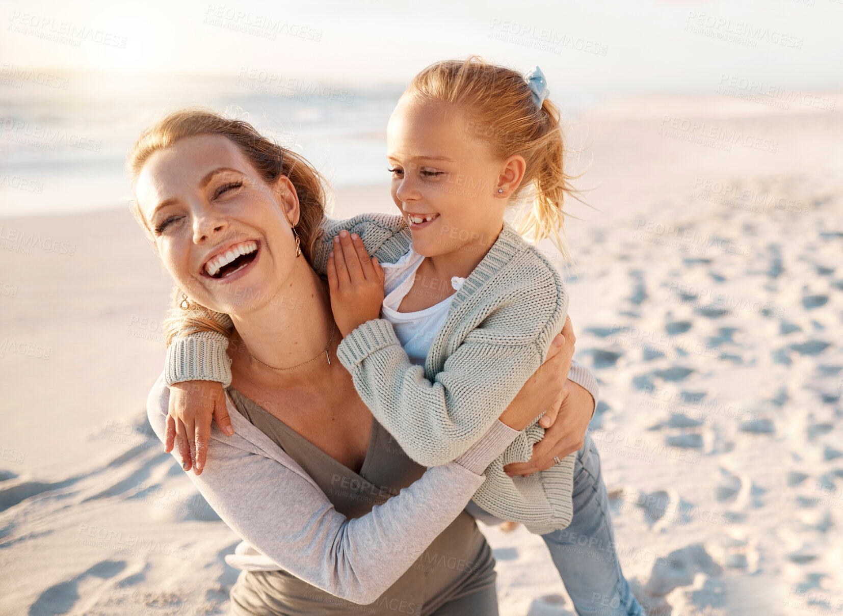 Buy stock photo Cheerful mother playing with her daughter. Young woman having fun with her child on the beach. Little girl bonding on the beach with her mother. Happy parent on holiday with her child by the sea