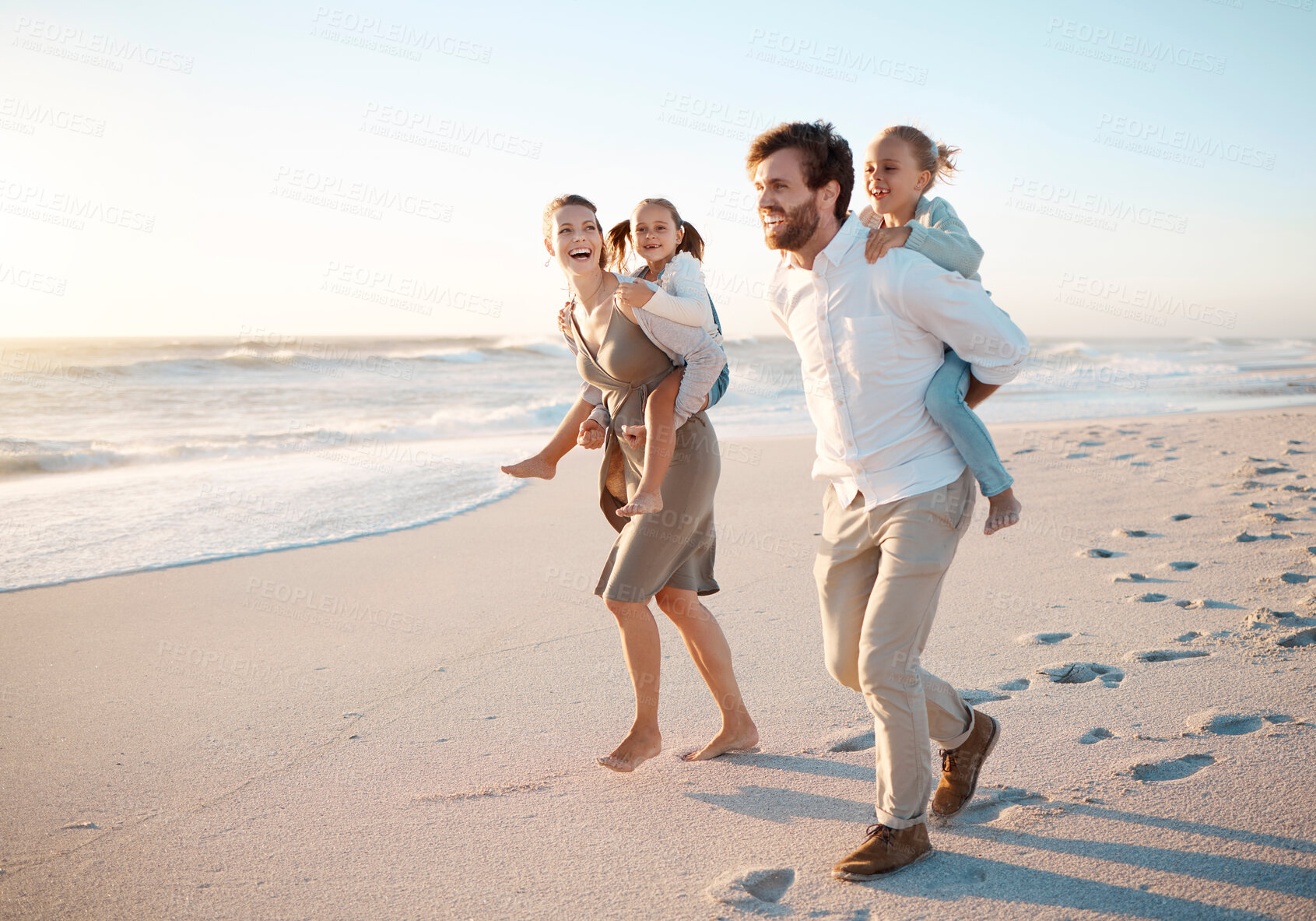 Buy stock photo Young family bonding on the beach together. Happy parents having fun with their children on holiday. Little girls playing with their parents on vacation by the sea. Caucasian family on holiday