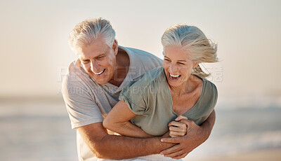 Buy stock photo Cheerful mature couple playing on the beach. Happy senior couple on holiday on the beach together. Married couple enjoying a beach holiday together. Couple playing during their vacation together