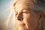 Closeup on the face of a mature woman on the beach. Beautiful senior woman enjoying the view on the beach. Face of a beautiful senior woman enjoying the view. Mature woman on holiday by the sea