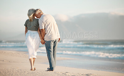 Buy stock photo Back of a senior couple walking on a beach together. Senior couple holding hands and walking on the beach. Mature couple enjoying a vacation together. Happy husband being affectionate with his wife