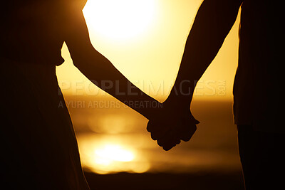 Hands of married couple on the beach at sunset. Silhouette of couple holding hands on the beach. Couple bonding on holiday by the sea. Couple in relationship bonding on vacation by the sea