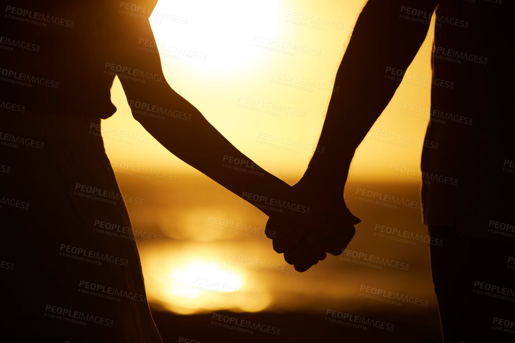 Buy stock photo Holding hands, couple and silhouette on beach at sunset for vacation or holiday outdoor. Behind man and woman in nature with peace, calm and ocean for love,  creative shadow and travel or freedom 