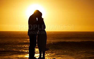 Mature couple bonding at sunset on the beach. Silhouette of senior couple being close on the beach. Mature married couple being affectionate on the beach. Couple enjoying a holiday by the sea