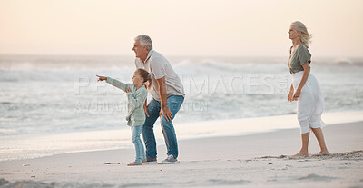 Buy stock photo Grandparents bonding with their grandchild. Grandfather talking to his grandchild on the beach. Little girl on holiday with her grandparents. Mature couple on vacation with their grandchild.