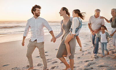 Buy stock photo happy family bonding on the beach. Married couple holding hands strolling on the beach. Family on holiday at the beach together. Parents and grandparents bonding with children on vacation.