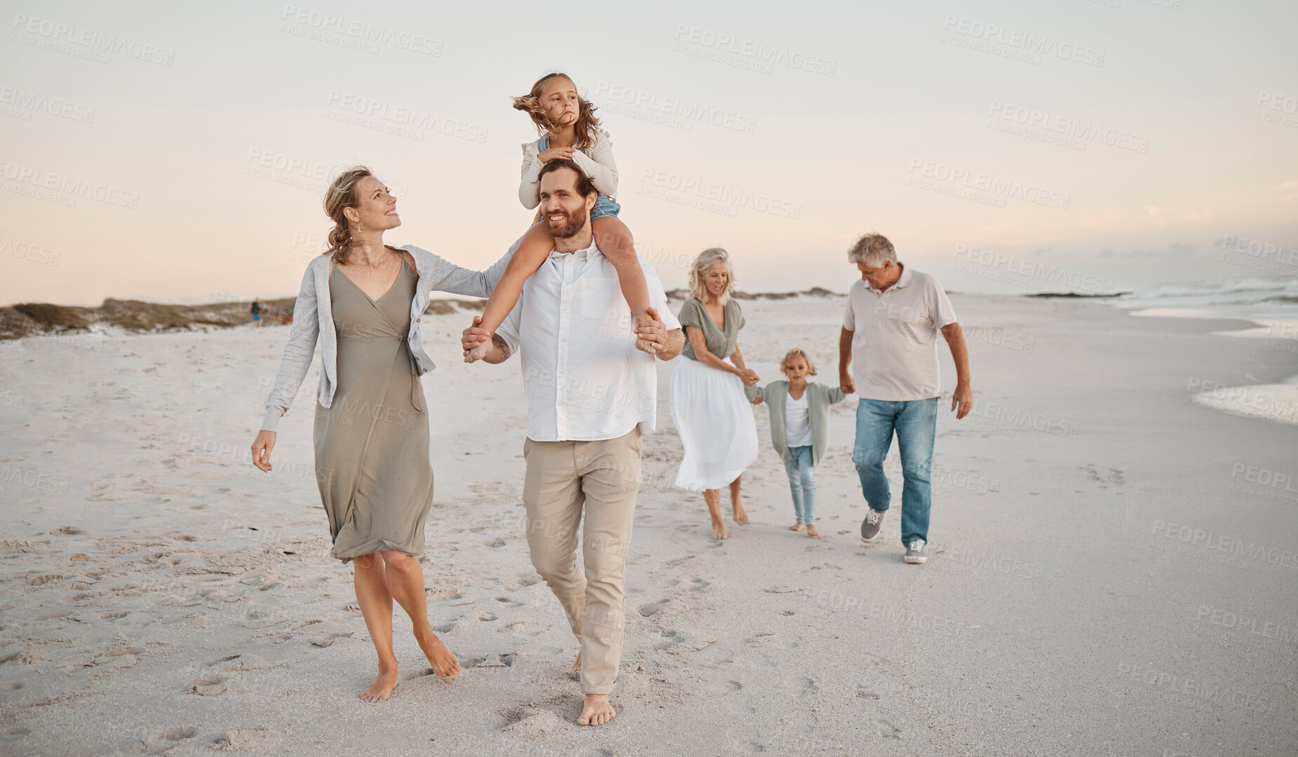 Buy stock photo Family walking on the beach together. Happy family bonding on holiday by the sea. Grandparents strolling on the beach with grandchildren. Caucasian family on the beach together on holiday
