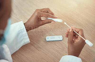 Hands of a doctor holding a covid test and swab sample. Closeup on hands of african american doctor using a corona virus test. Dedicated gp holding covid test sample in the clinic