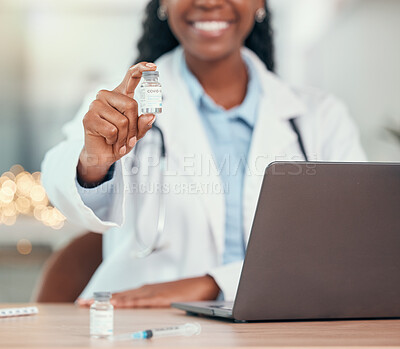 Smiling doctor sitting at her desk holding a vial of covid vaccine. African american doctor holding a bottle of corona virus antidote. Medical physician holding the covid cure