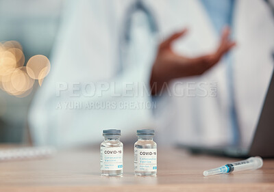 bottles of covid antidote on the table of a doctor. Corona virus vaccine on a doctors table with a needle. A syringe and covid cure on the table in a hospital. African american doctor in their office