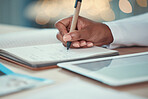 Closeup on hands of a doctor writing in a journal. Doctor planning in a notebook. African american doctor using a digital tablet in the hospital. Specialist using a smart device