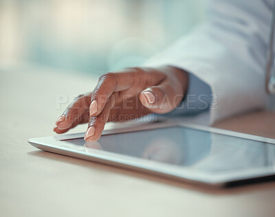 Closeup on fingers of doctor working on a digital tablet. Medical doctor using an online app on a wireless tablet. African american doctor browsing the internet on a tablet