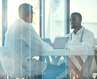 Two doctors talking in a meeting. Colleagues collaborate in a medical meeting in the hospital. Young medical coworkers planning together in a meeting. Caring medical professionals at work