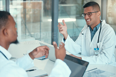 Two doctors working together to collaborate. Colleagues working together in a meeting in the hospital. Young doctors brainstorm in a meeting. Happy doctors talking at work