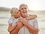 Portrait of a happy senior caucasian couple standing and embracing each other on a day out at the beach. Mature husband and wife smiling and showing affection in nature