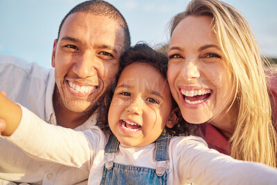 Buy stock photo Portrait of a mixed race family taking a selfie and smiling outside on a sunny day. Mother and father having fun with their cute daughter at the beach