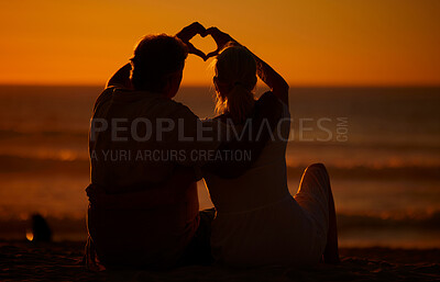 Buy stock photo Close up of an unrecognizable couple making a heart gesture with their hands at the beach during a beautiful sunset