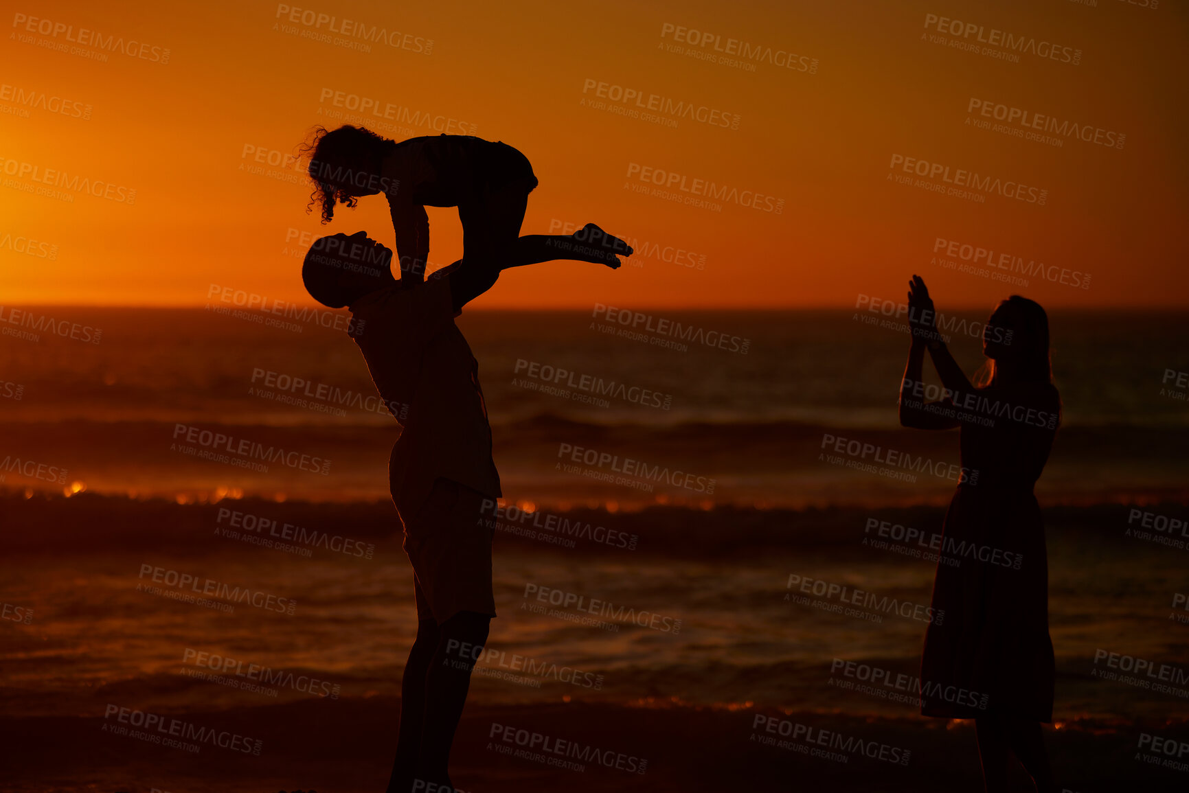 Buy stock photo A young family silhouetted on the beach while playing together. Cheerful family with one child, two parents and daughter having fun during sunset at the beach