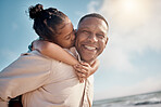 Smiling mixed race single father carrying little daughter on piggyback with copyspace. Adorable, happy, hispanic girl bonding with parent and kissing cheek on beach. Man and child enjoying free time