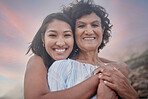Portrait of a young hispanic woman spending the day at the beach with her elderly mother. Mixed race female and her mother smiling at the beach and hugging each other