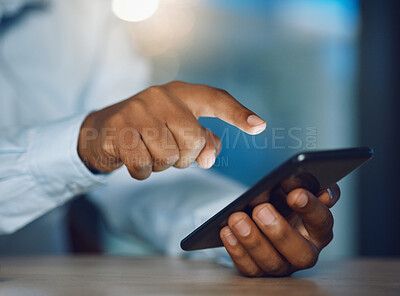 Closeup hands of african man using a phone while sitting in his office. African american business man sending a text message while working late at night at his work. Putting in overtime after hours